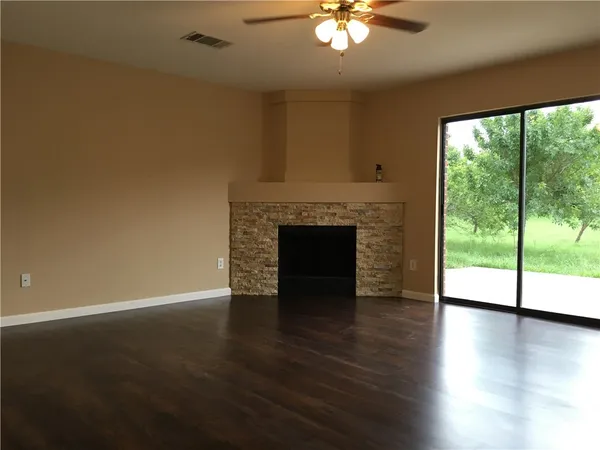 a view of an empty room with wooden floor and a fireplace