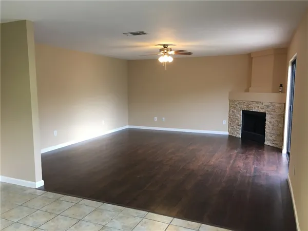 an empty room with wooden floor fireplace and windows