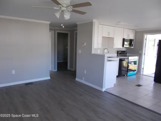 a view of a kitchen with refrigerator and wooden floor