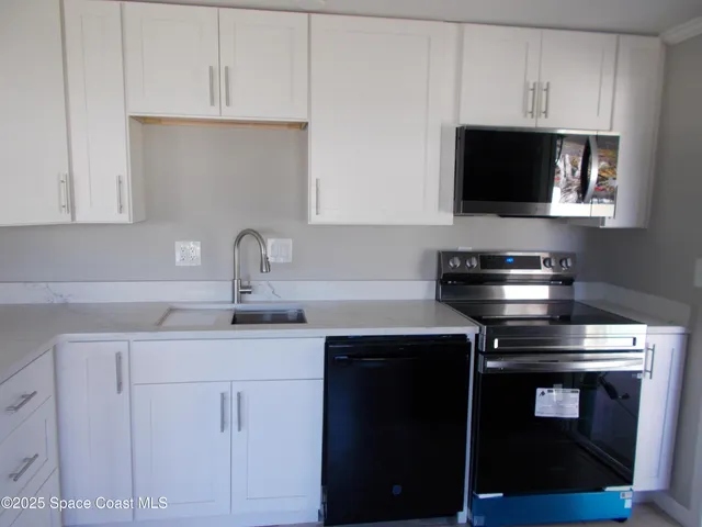 a kitchen with white cabinets and black appliances