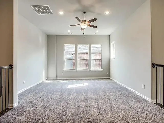 an empty room with windows and ceiling fan
