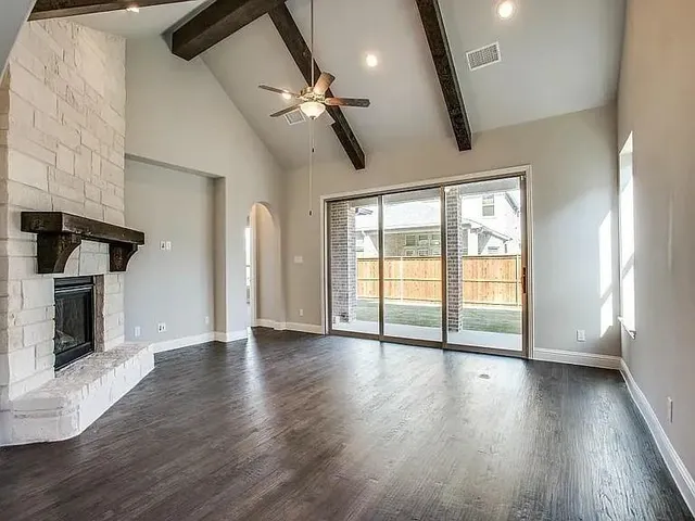 an empty room with wooden floor fireplace and windows