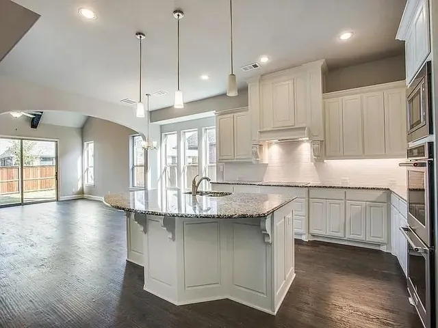 a kitchen with stainless steel appliances granite countertop a sink a stove and a wooden floors