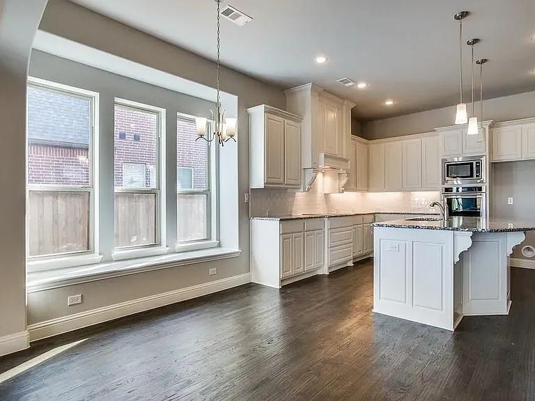 1322 Rolling Thunder Road Frisco, TX 75036 - Photo 10 of 20 a kitchen with stainless steel appliances granite countertop a stove a sink and white cabinets with wooden floor