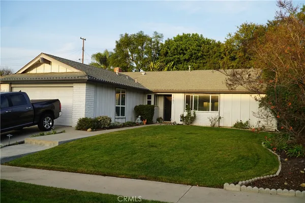 a front view of a house with a garden and trees