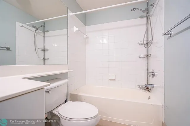 a bathroom with a sink a toilet a mirror a vanity a bathtub and shower