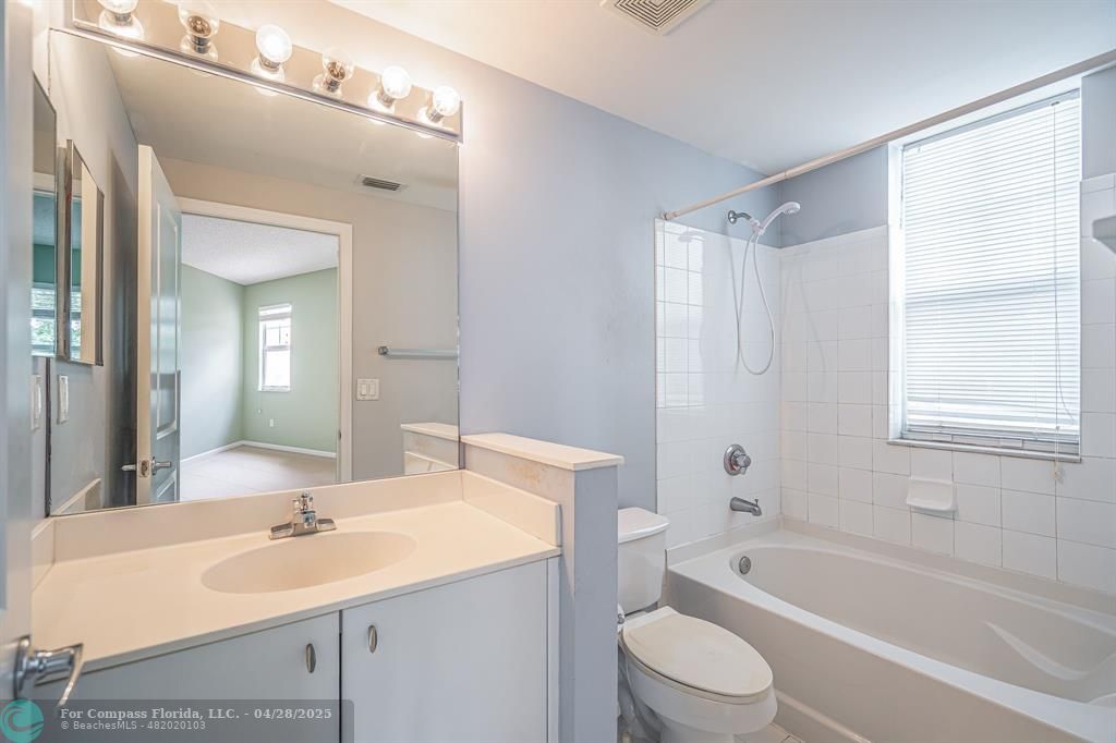 5840 West Sample Road, Unit 301 Coral Springs, FL 33067 - Photo 18 of 19 a bathroom with a sink a toilet a mirror a vanity a bathtub and shower