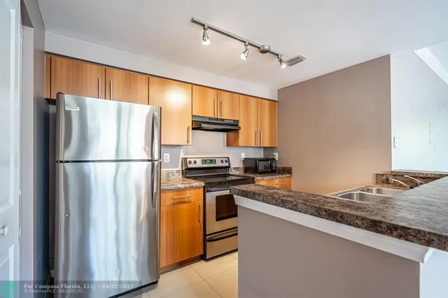 a kitchen with stainless steel appliances granite countertop a refrigerator a stove and a sink