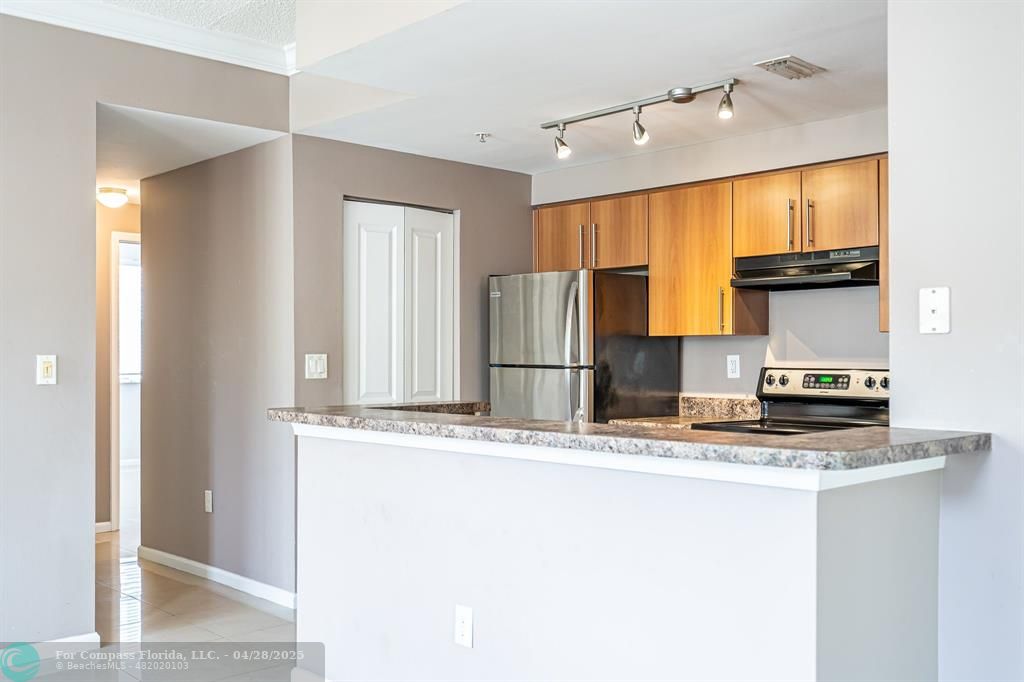 5840 West Sample Road, Unit 301 Coral Springs, FL 33067 - Photo 6 of 19 a kitchen with stainless steel appliances granite countertop a sink and a refrigerator