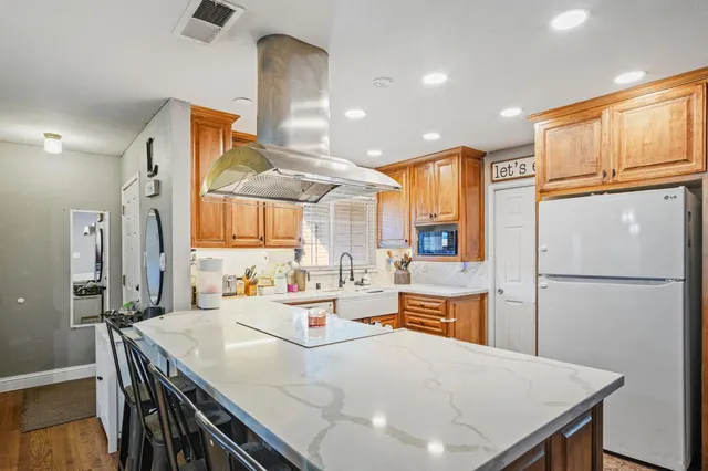 a kitchen with a refrigerator a sink dishwasher and white cabinets with wooden floor