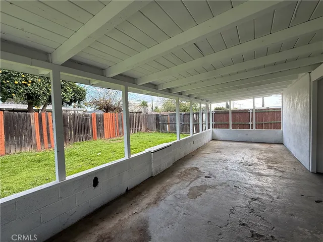 a view of an empty room with wooden floor and a kitchen