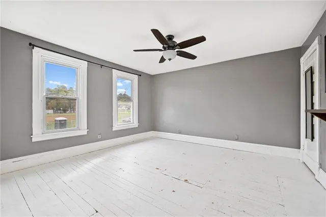 an empty room with windows and fan