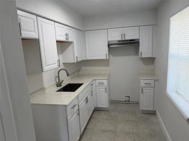a kitchen with white cabinets and sink