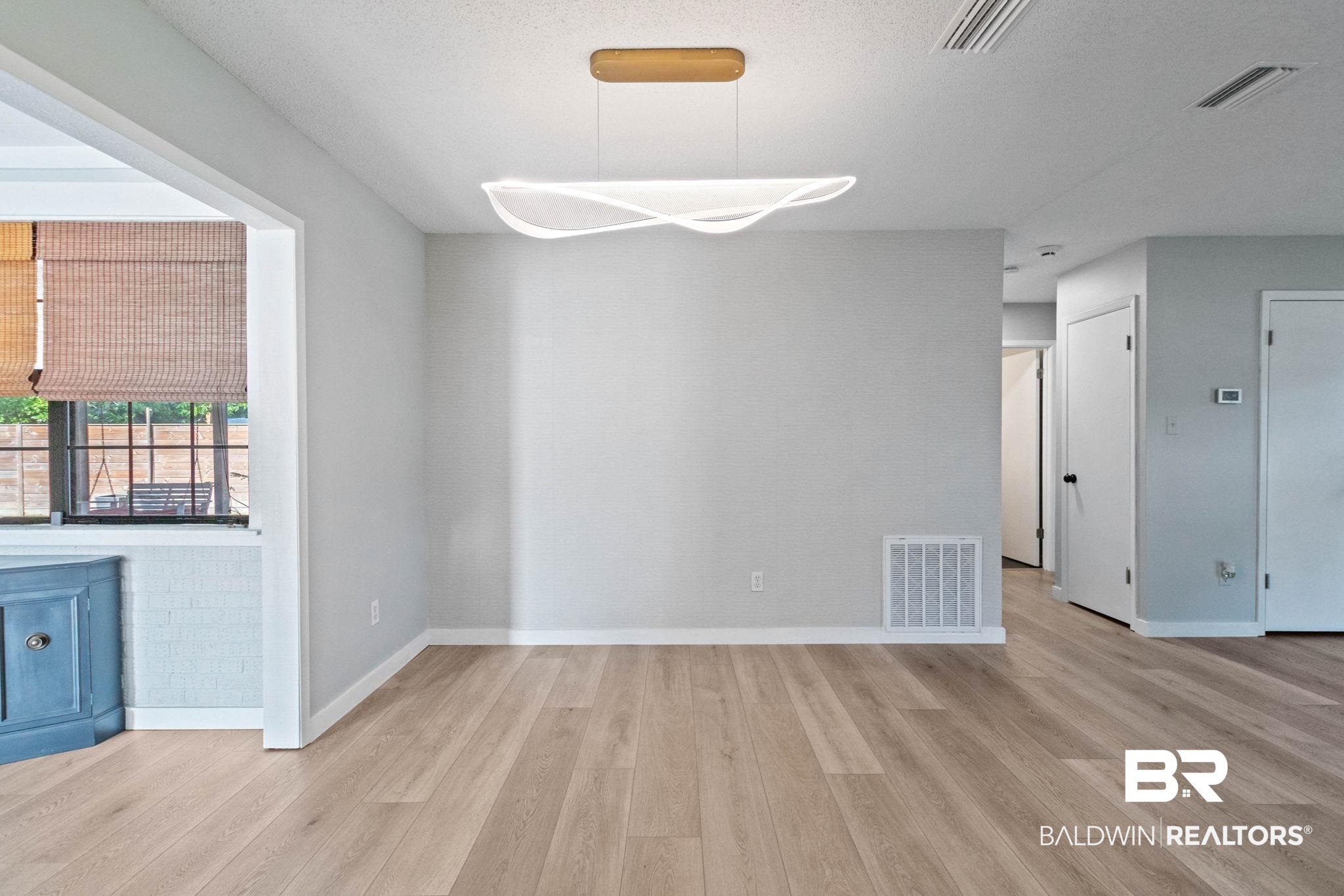 524 Ariel Avenue Foley, AL 36535 - Photo 14 of 37 Spacious interior featuring wood-finish flooring, a contemporary linear chandelier, neutral wall tones, and white baseboards
