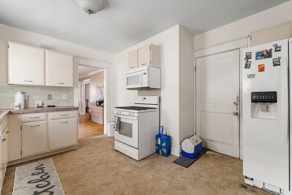 a kitchen with a refrigerator sink and white cabinets