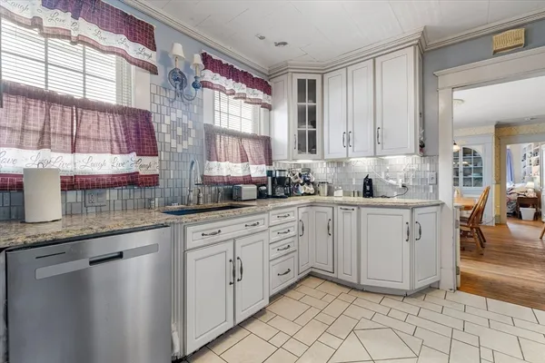 a kitchen with granite countertop white cabinets white appliances a sink and a window