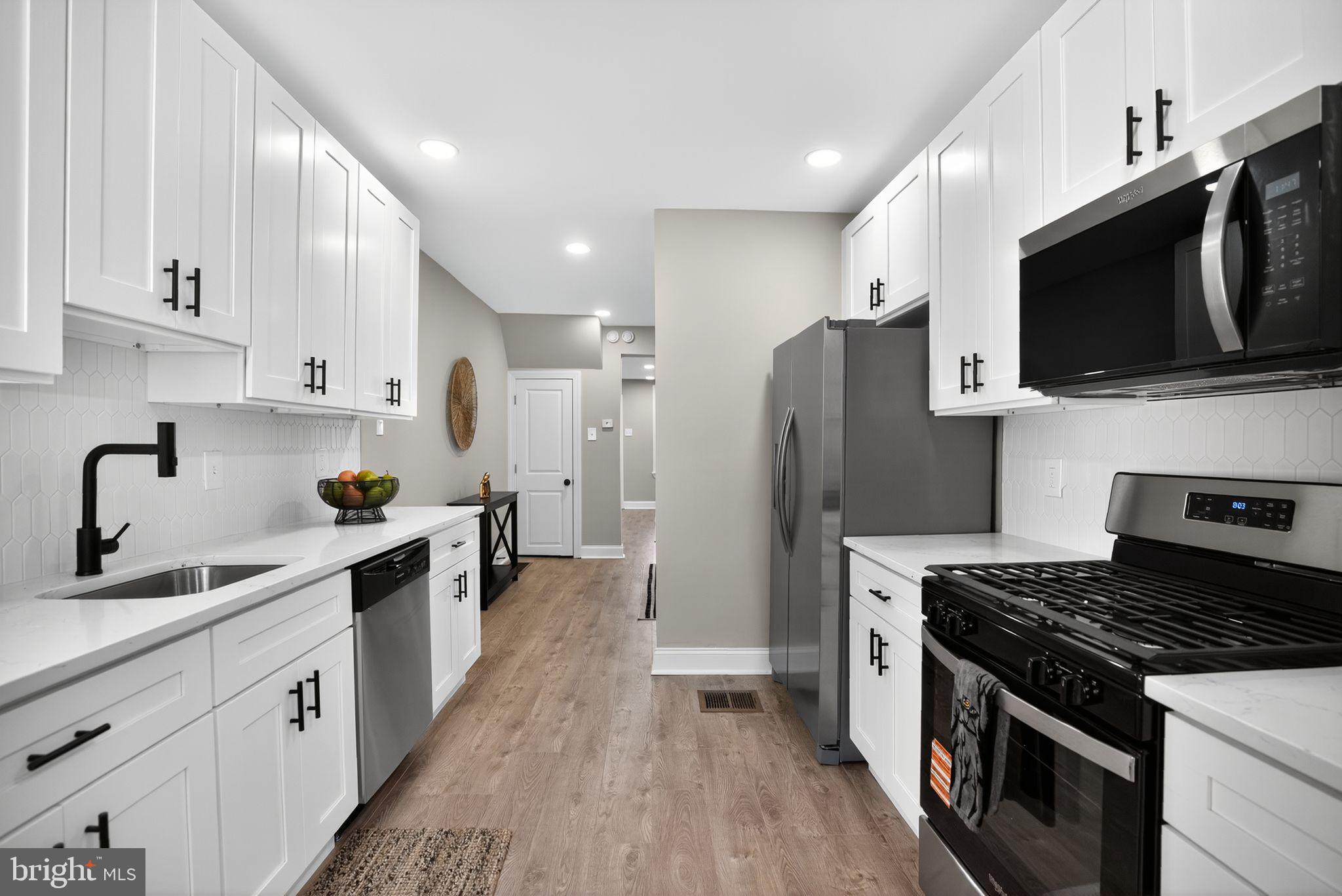 258 West Sheldon Street Philadelphia, PA 19120 - Photo 13 of 29 a kitchen with stainless steel appliances a sink dishwasher a refrigerator and a stove top oven with wooden floor