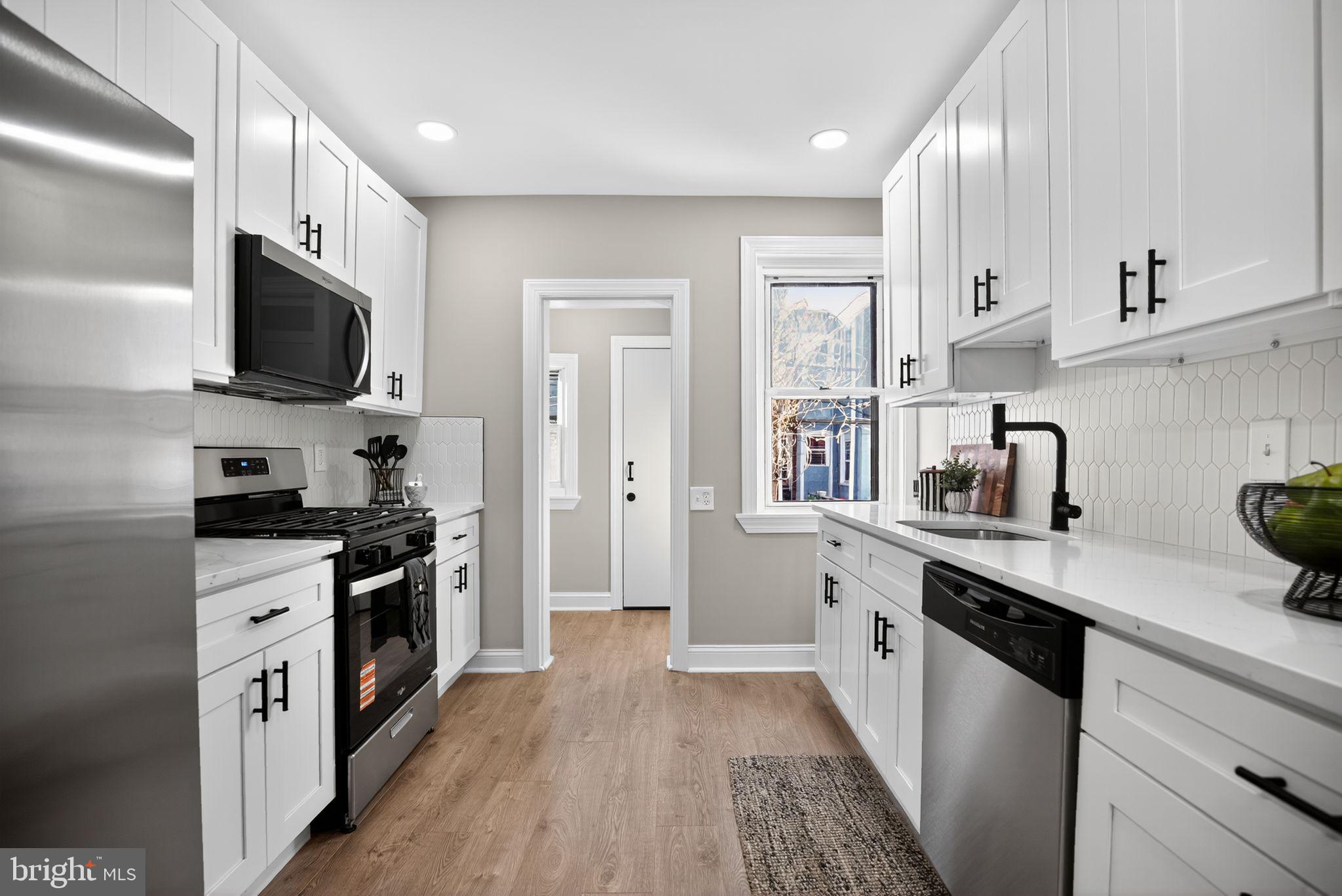 258 West Sheldon Street Philadelphia, PA 19120 - Photo 15 of 29 a kitchen with stainless steel appliances a stove top oven a sink a refrigerator white cabinets and wooden floor