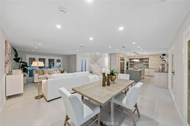 a kitchen with kitchen island a stove a refrigerator a sink a dining table and chairs with wooden floor