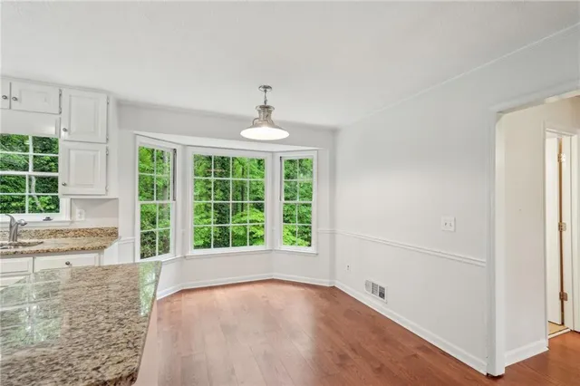 a kitchen with stainless steel appliances granite countertop a stove top oven a sink dishwasher and a refrigerator with wooden floor