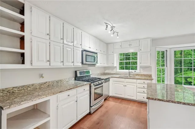 a kitchen with granite countertop white cabinets and a stove