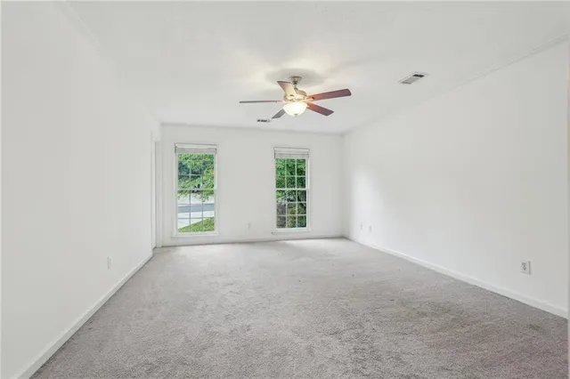 an empty room with windows and chandelier fan