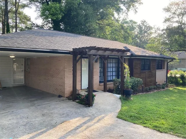 a view of a house with a yard plants and large tree