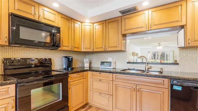 a kitchen with stainless steel appliances granite countertop a sink a stove and a microwave