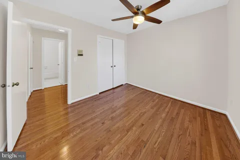 an empty room with wooden floor a ceiling fan and closet