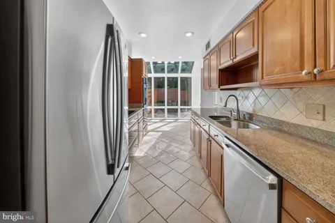 a kitchen with stainless steel appliances granite countertop a sink a stove a microwave a refrigerator and cabinets