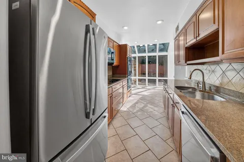 a kitchen with stainless steel appliances granite countertop a sink and a refrigerator