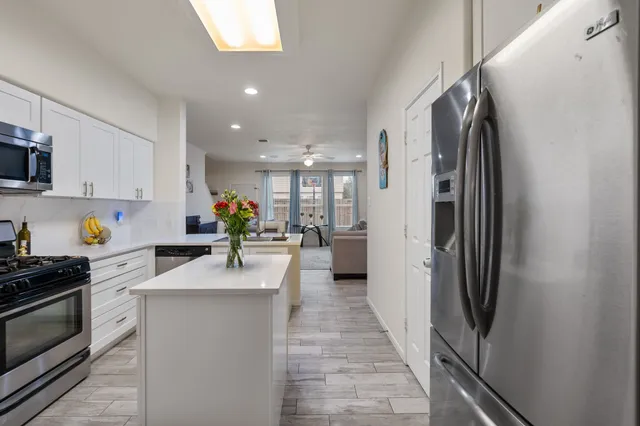 a kitchen with stainless steel appliances granite countertop a refrigerator a stove and a sink