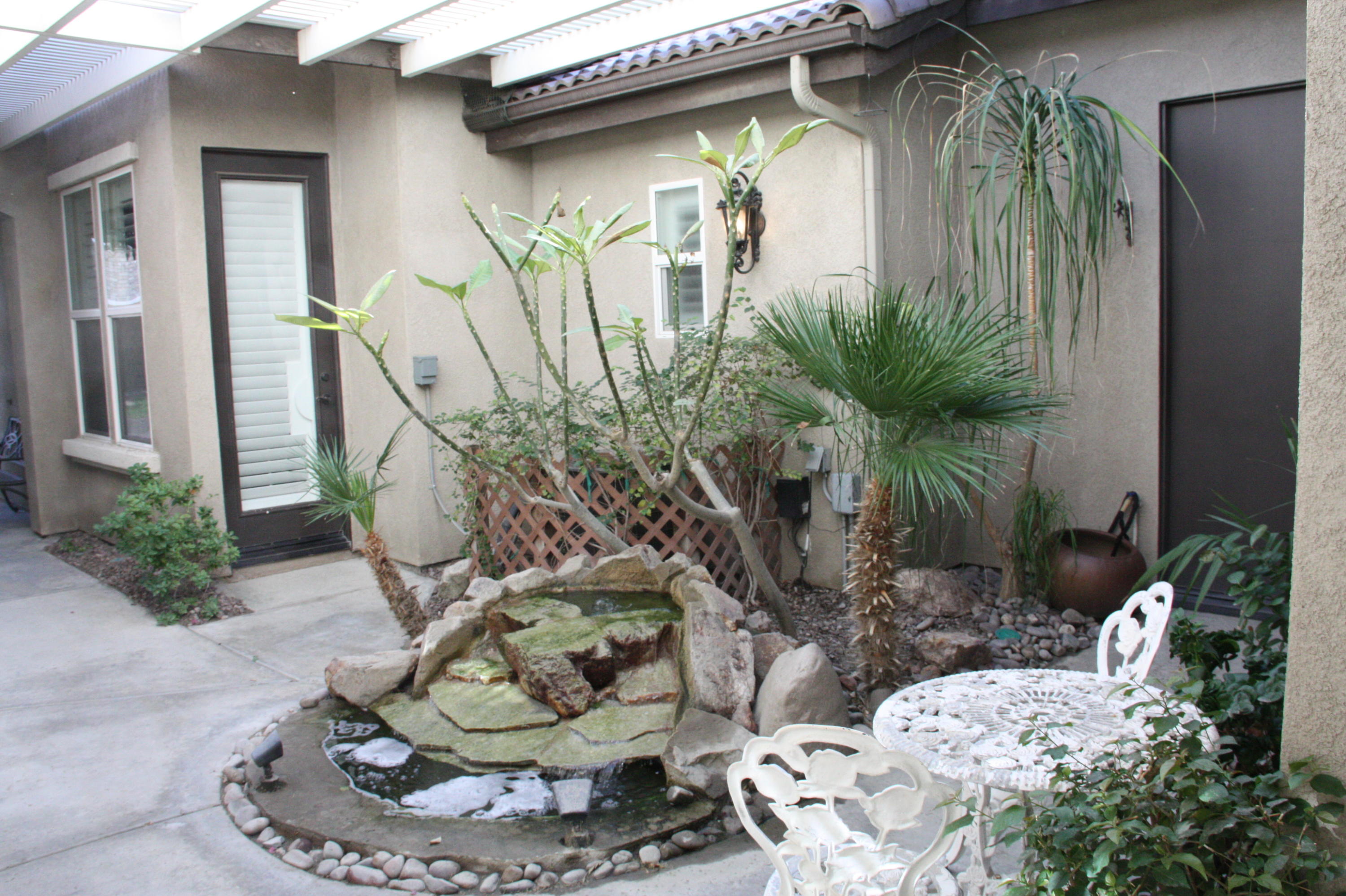 49475 Redford Way Indio, CA 92201 - Photo 2 of 58 a vase of flowers sitting on a table with chairs
