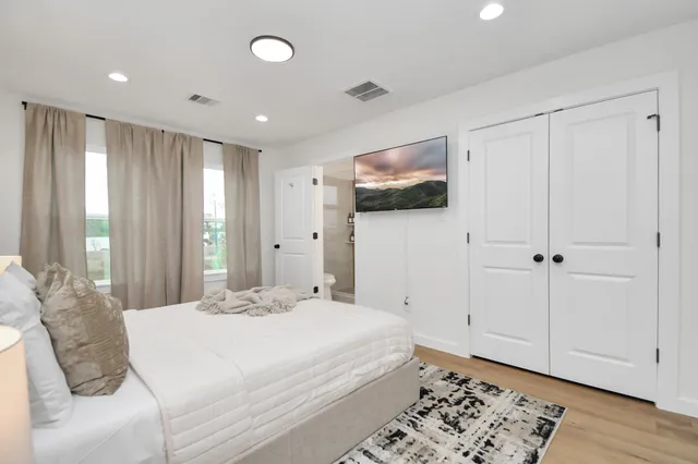 a spacious bedroom with a bed and a flat screen tv
