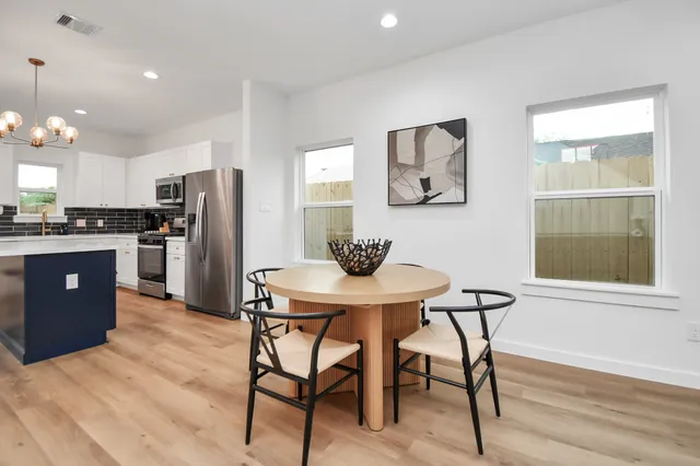 a kitchen with stainless steel appliances kitchen island granite countertop a dining table chairs and refrigerator