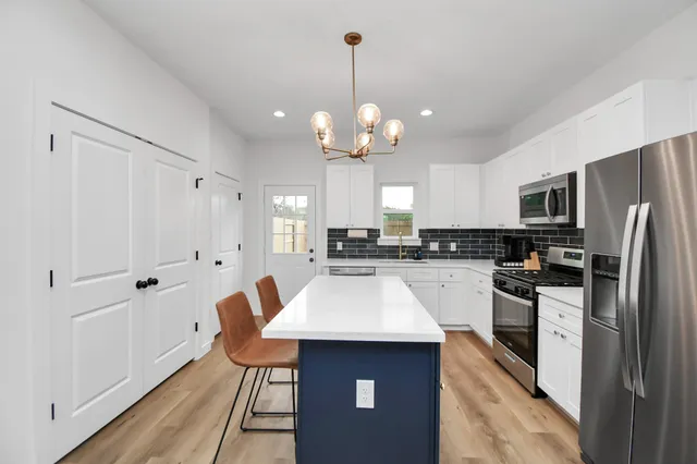 a kitchen with kitchen island granite countertop stainless steel appliances a stove refrigerator and cabinets