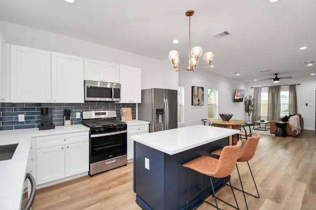 a kitchen with stainless steel appliances a stove center island a refrigerator and a stove with wooden floor