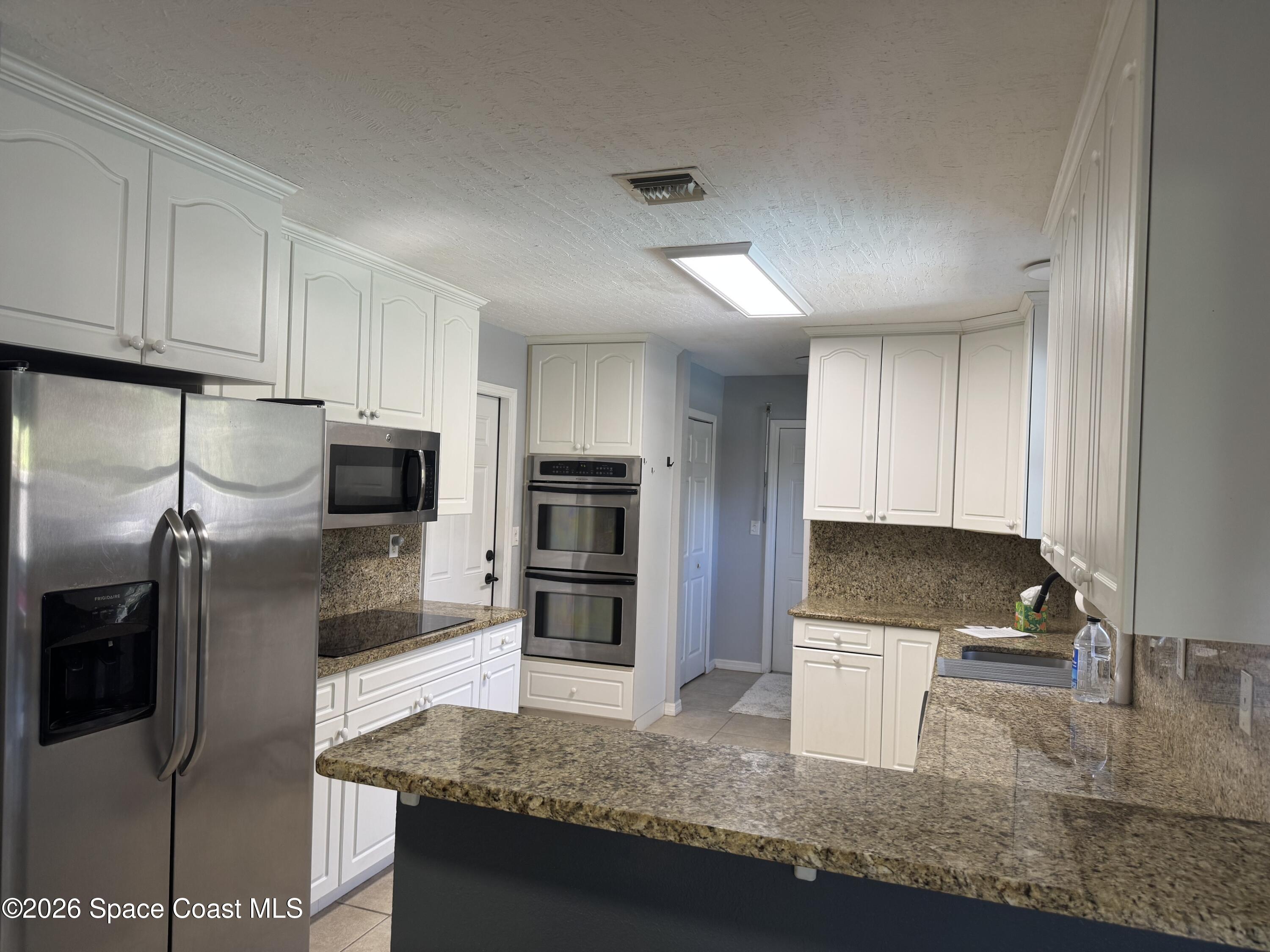 2135 South River Road Melbourne Beach, FL 32951 - Photo 3 of 14 a kitchen with stainless steel appliances granite countertop a sink a stove and a refrigerator