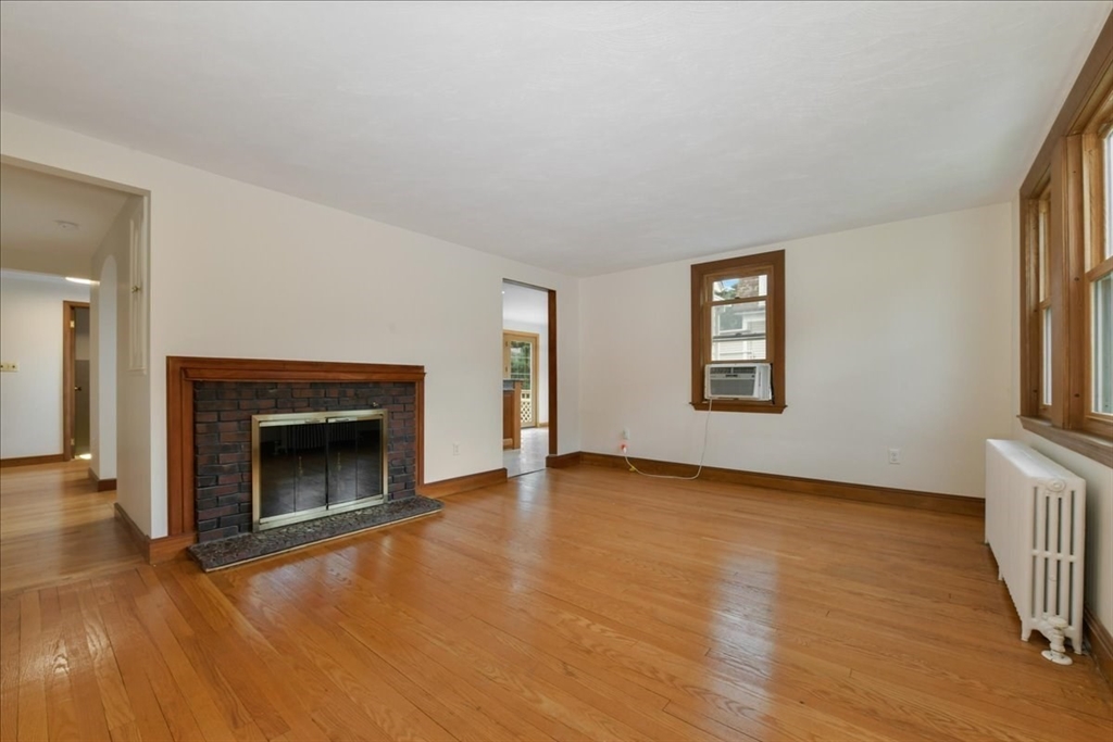 102 Border Street Dedham, MA 02026 - Photo 3 of 34 an empty room with wooden floor fireplace and windows