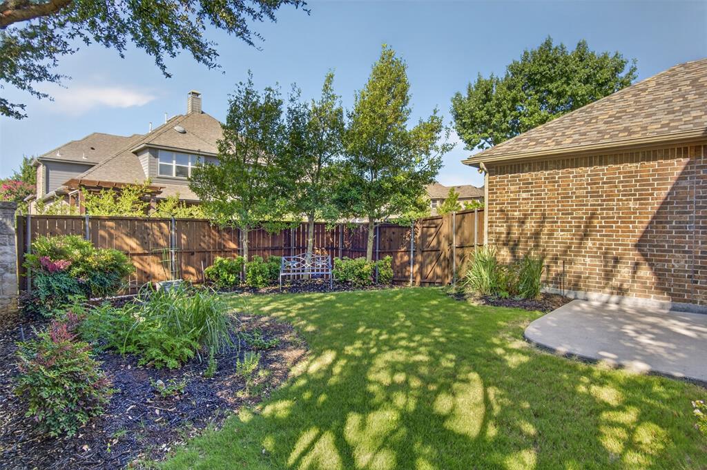 842 Sun Meadow Road Allen, TX 75013 - Photo 4 of 39 Expansive backyard featuring a manicured lawn, established landscaping beds, a wood privacy fence, and a concrete patio pad