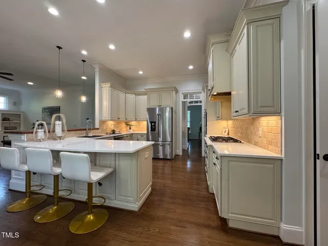 a dining hall with stainless steel appliances granite countertop a refrigerator and a stove top oven with wooden floor