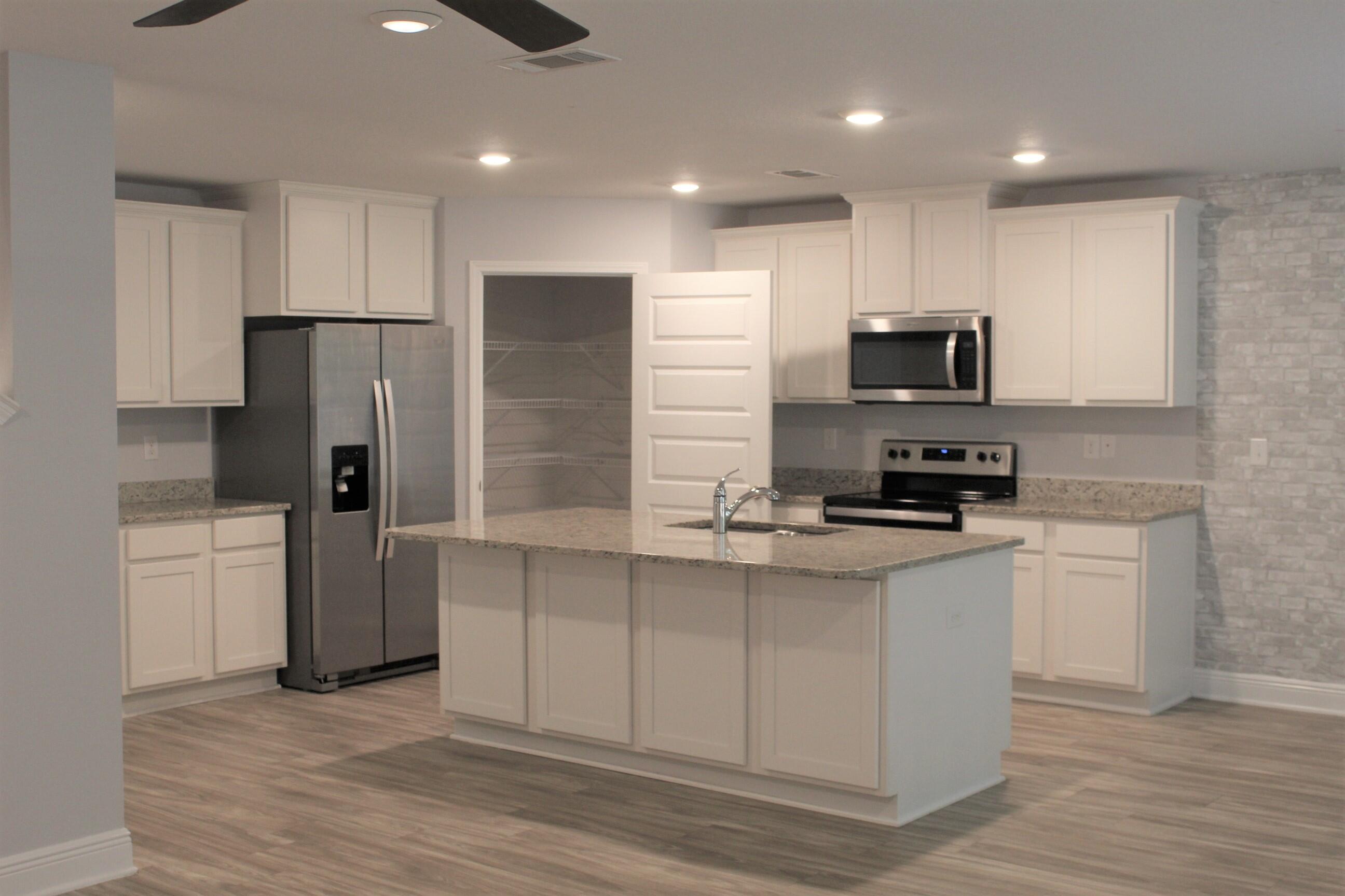 3139 Heritage Oaks Circle Navarre, FL 32566 - Photo 12 of 34 a kitchen with stainless steel appliances a refrigerator a stove top oven a sink and dishwasher