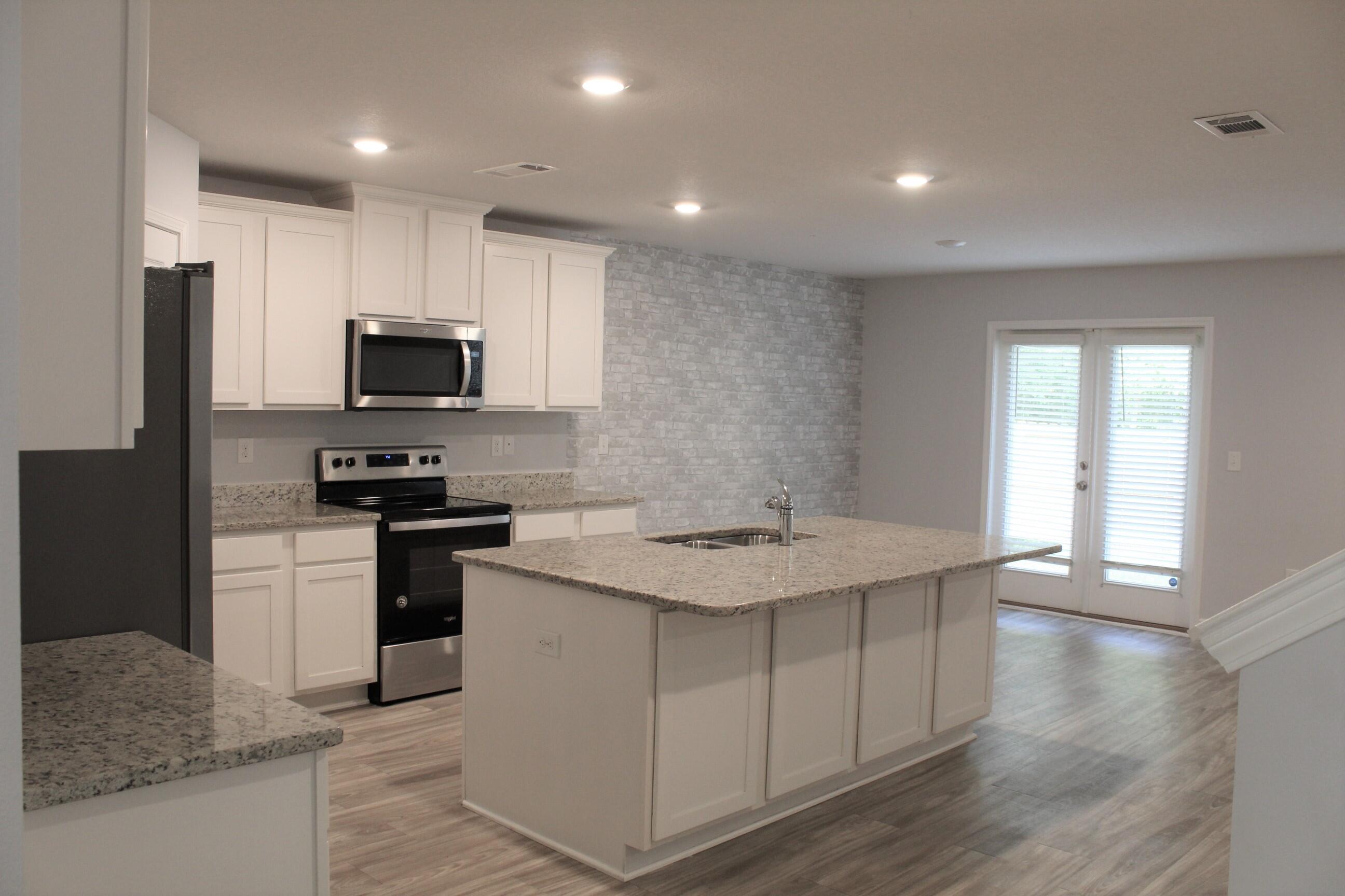 3139 Heritage Oaks Circle Navarre, FL 32566 - Photo 6 of 34 a kitchen with stainless steel appliances kitchen island granite countertop a sink a stove and a refrigerator
