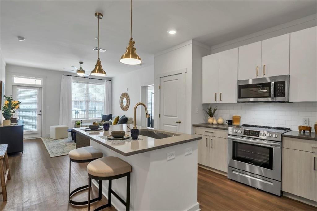 a kitchen with stainless steel appliances granite countertop a stove a sink a microwave a refrigerator a stove a dining table and chairs with wooden floor