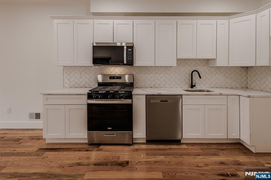 29 Kent Street Newark, NJ 07108 - Photo 2 of 30 a kitchen with stainless steel appliances white cabinets and a stove top oven