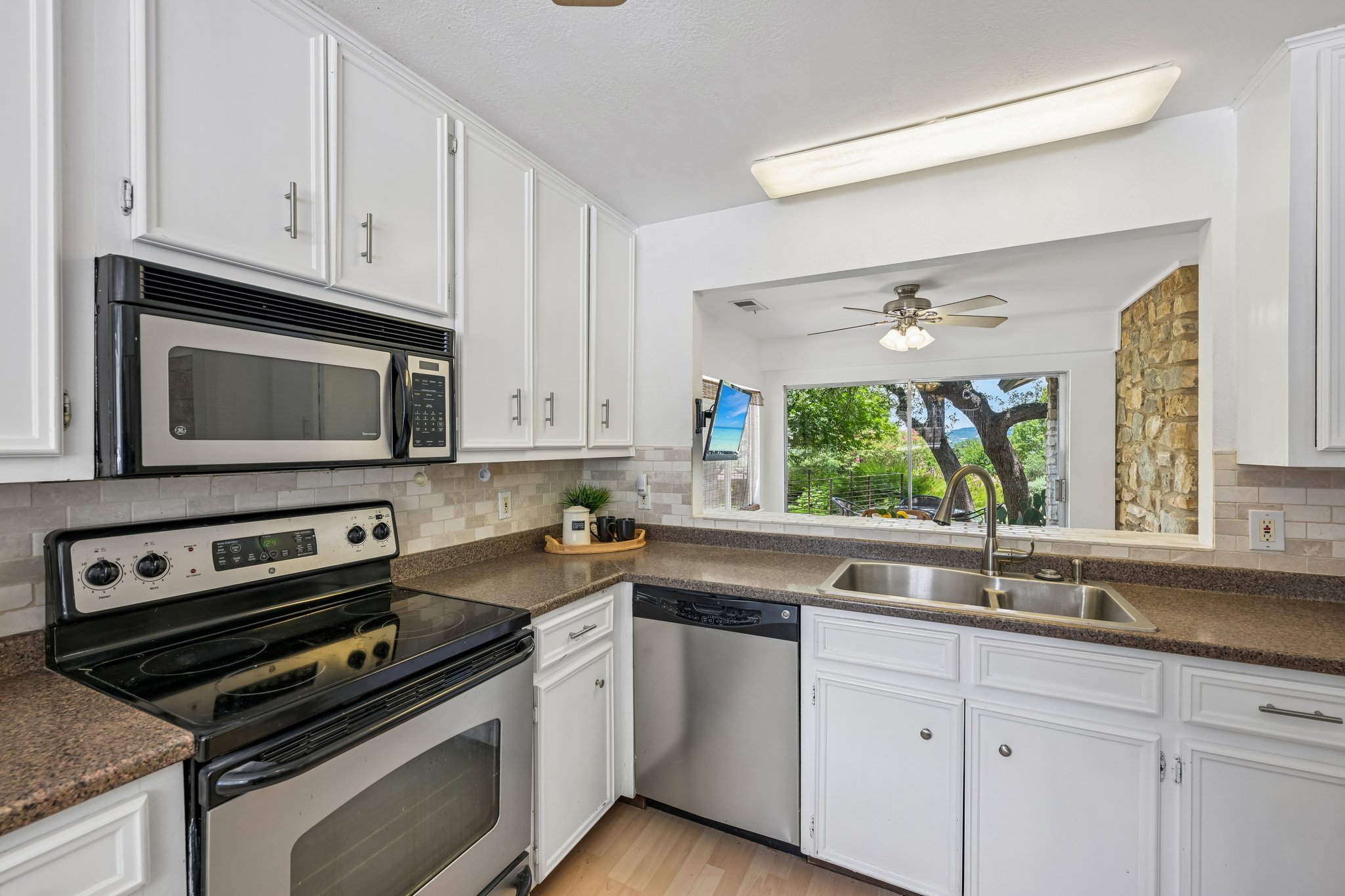 13101 Travis View Loop Austin, TX 78732 - Photo 7 of 27 A compact kitchen offering a pass-through window with scenic outdoor views.