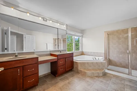 a spacious bathroom with a tub sink shower and mirror