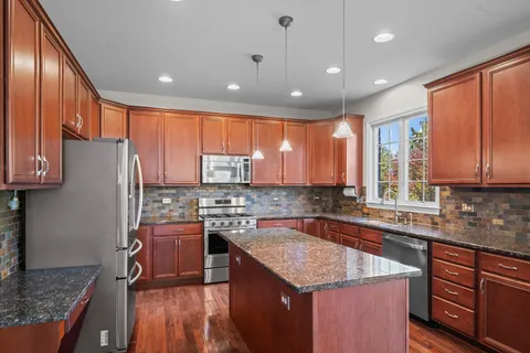 a kitchen with stainless steel appliances granite countertop sink stove top oven refrigerator and cabinets
