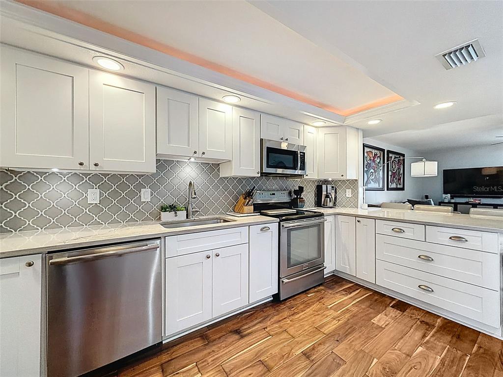 433 Paula Drive South, Unit 23 Dunedin, FL 34698 - Photo 11 of 56 a kitchen with granite countertop white cabinets and white appliances