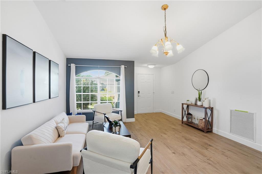 272 Johnnycake Drive Naples, FL 34110 - Photo 2 of 33 a living room with furniture chandelier and a large window